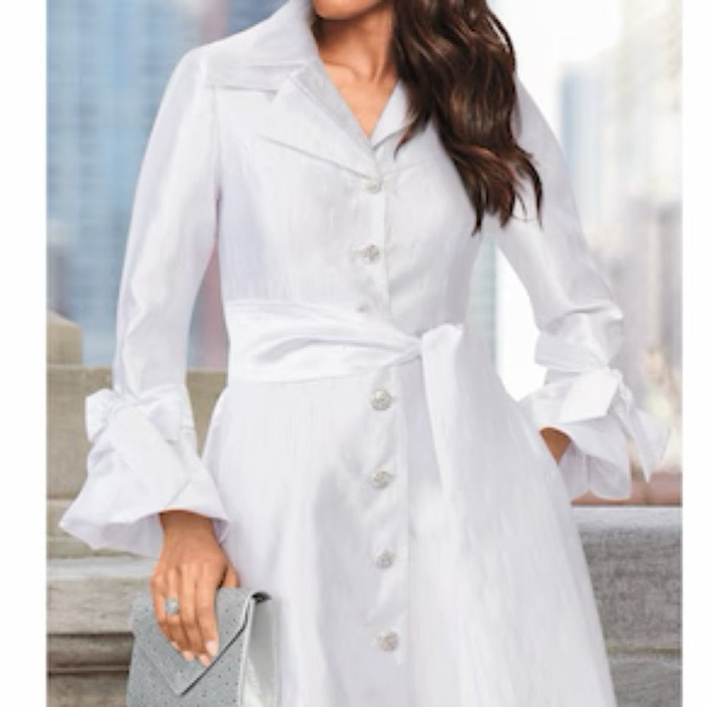 Woman wearing a white dress with ruffled sleeves in an indoor setting