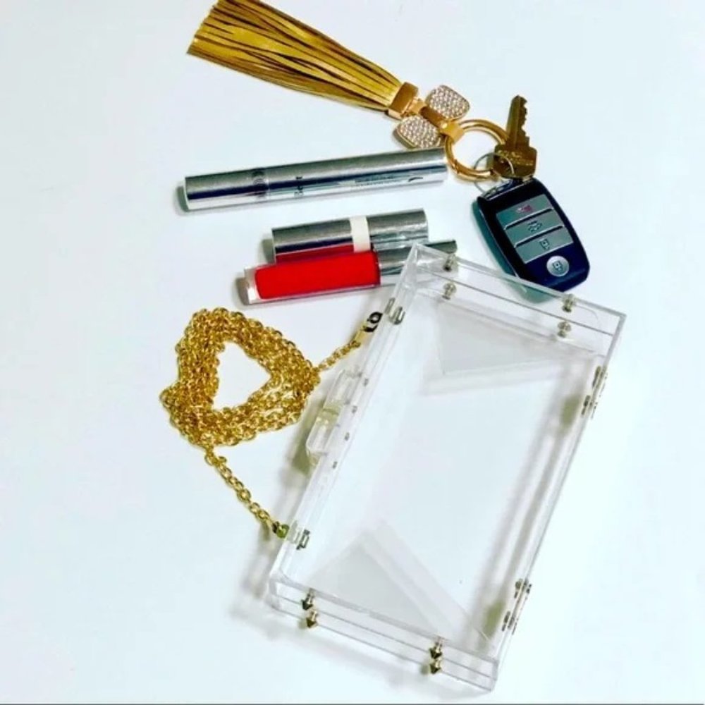 Clear acrylic phone case with keychain and lip glosses on a white background