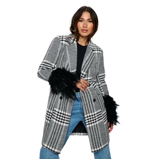 Woman wearing a black and white checkered coat with fur cuffs on a white background
