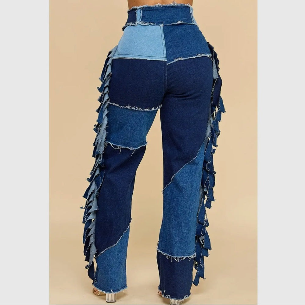 Blue denim pants with ruffled details on a beige background