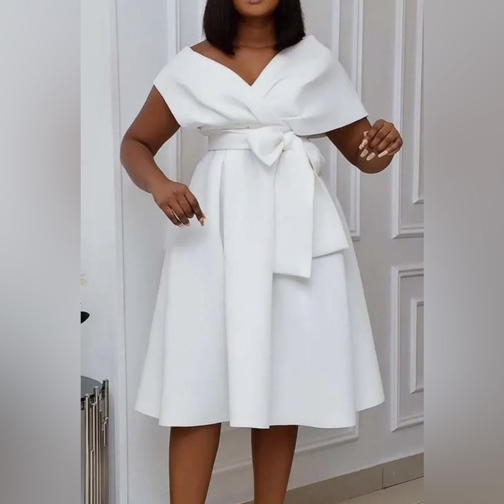 White dress with a bow detail worn by a person against a neutral background