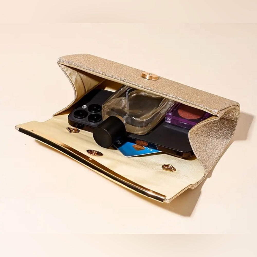 Gold clutch with phone, cards, and makeup items on a beige background